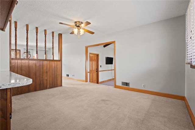 unfurnished room featuring a textured ceiling, carpet flooring, visible vents, baseboards, and a ceiling fan