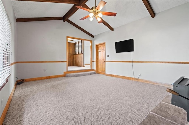 unfurnished living room with lofted ceiling with beams, a textured ceiling, carpet flooring, a ceiling fan, and baseboards