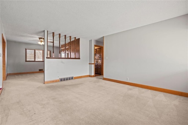 unfurnished living room featuring carpet floors, visible vents, ceiling fan, a textured ceiling, and baseboards