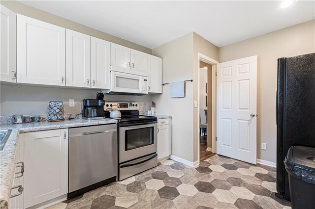 kitchen featuring stainless steel appliances, white cabinetry, and light stone counters