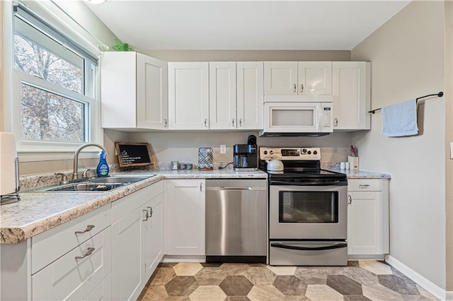 kitchen featuring light stone countertops, appliances with stainless steel finishes, sink, and white cabinets