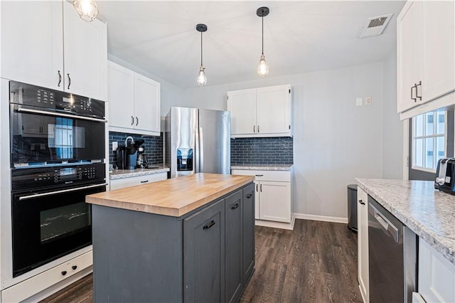 kitchen featuring wooden counters, appliances with stainless steel finishes, white cabinetry, tasteful backsplash, and a kitchen island