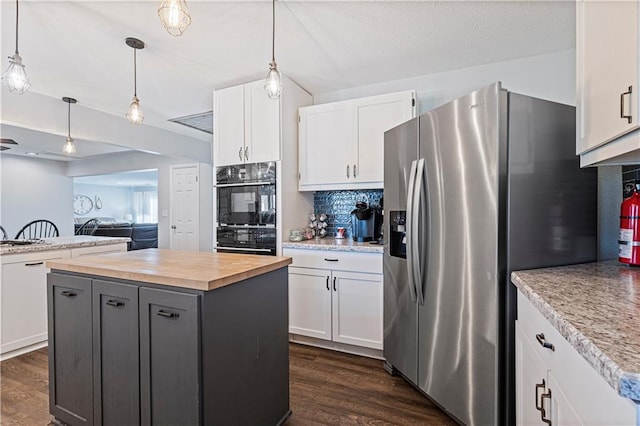 kitchen with stainless steel refrigerator with ice dispenser, decorative light fixtures, a center island, decorative backsplash, and white cabinets