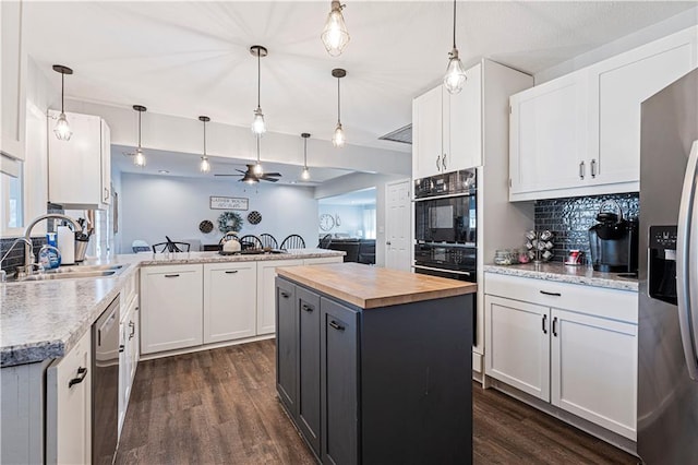 kitchen with sink, hanging light fixtures, kitchen peninsula, a kitchen island, and white cabinets