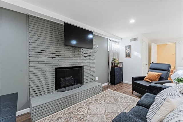 living room featuring hardwood / wood-style flooring and a brick fireplace