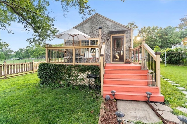 rear view of house featuring a deck and a lawn