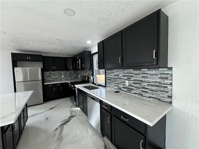 kitchen with light stone countertops, sink, a textured ceiling, decorative backsplash, and appliances with stainless steel finishes