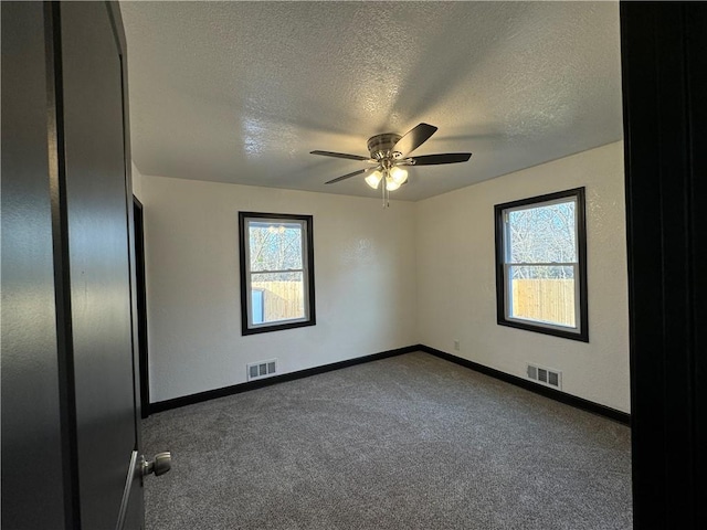 carpeted empty room featuring ceiling fan and a textured ceiling