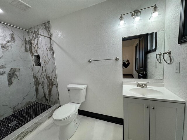 bathroom featuring vanity, toilet, and tiled shower