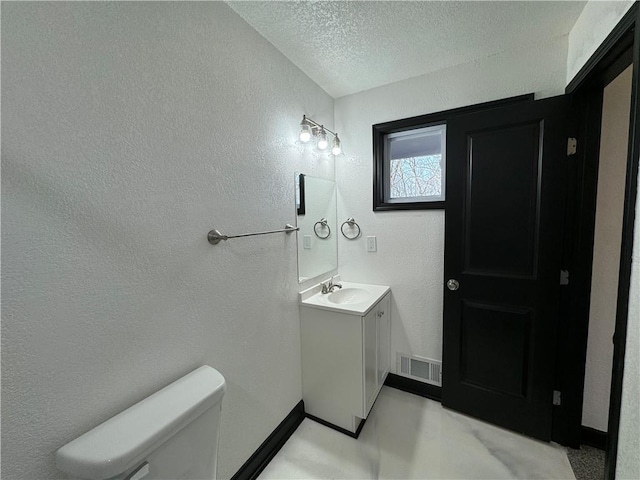 bathroom with vanity, a textured ceiling, and toilet