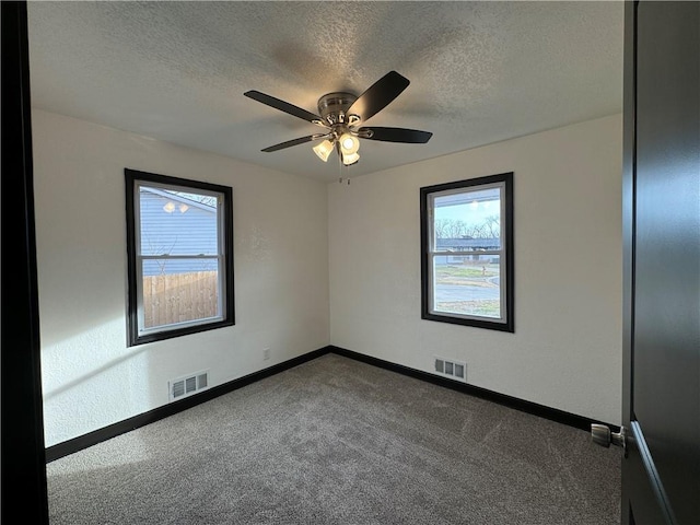 carpeted spare room with a textured ceiling and ceiling fan