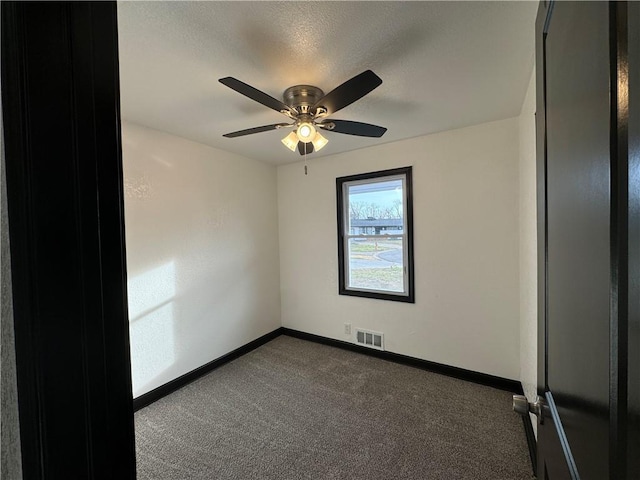 spare room with ceiling fan, a textured ceiling, and dark colored carpet