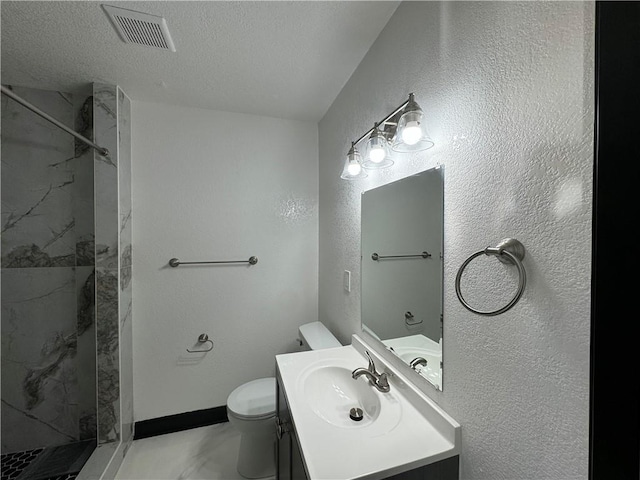 bathroom featuring vanity, a tile shower, a textured ceiling, and toilet