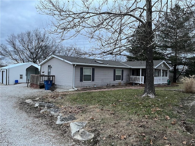 view of front of property featuring an outbuilding, a front lawn, a carport, and a sunroom