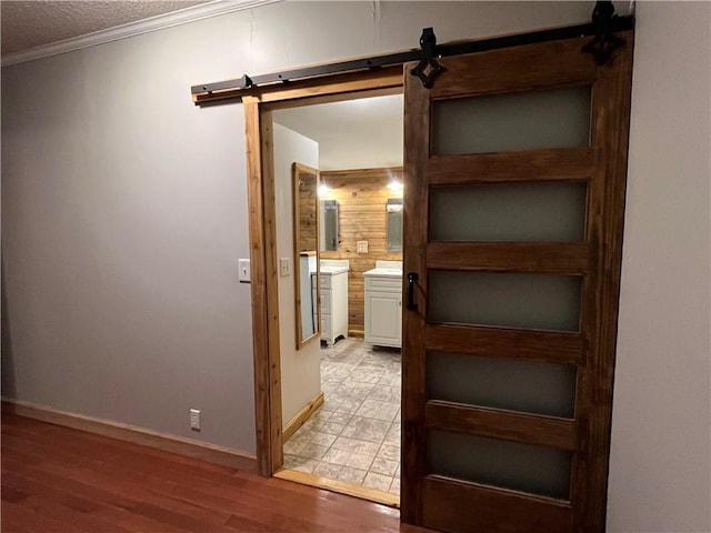 hallway featuring hardwood / wood-style floors, a barn door, a textured ceiling, and ornamental molding