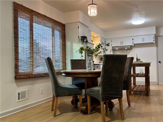 dining room with light wood-type flooring and a notable chandelier