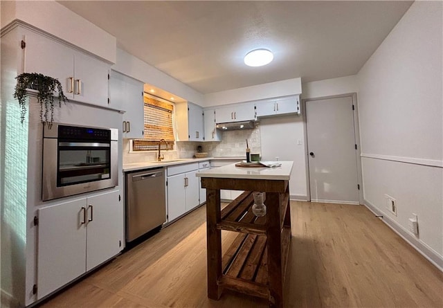 kitchen featuring backsplash, stainless steel appliances, light hardwood / wood-style flooring, and sink