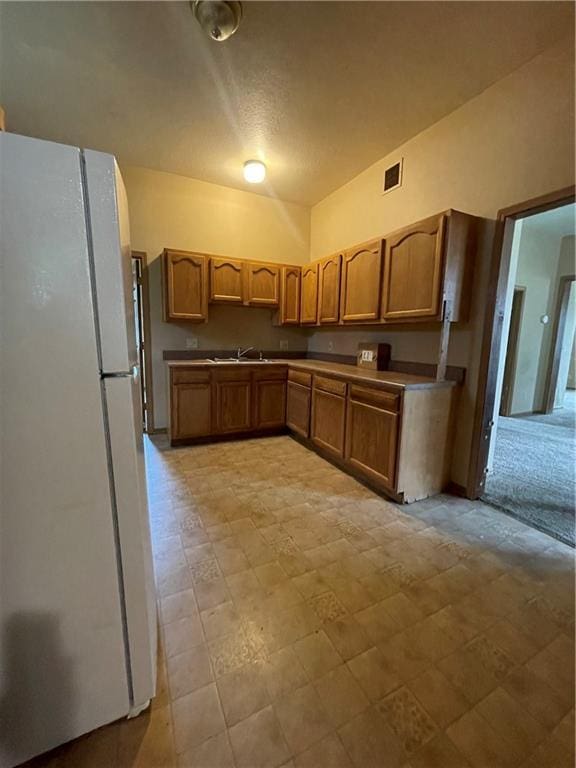 kitchen featuring sink, white fridge, and vaulted ceiling