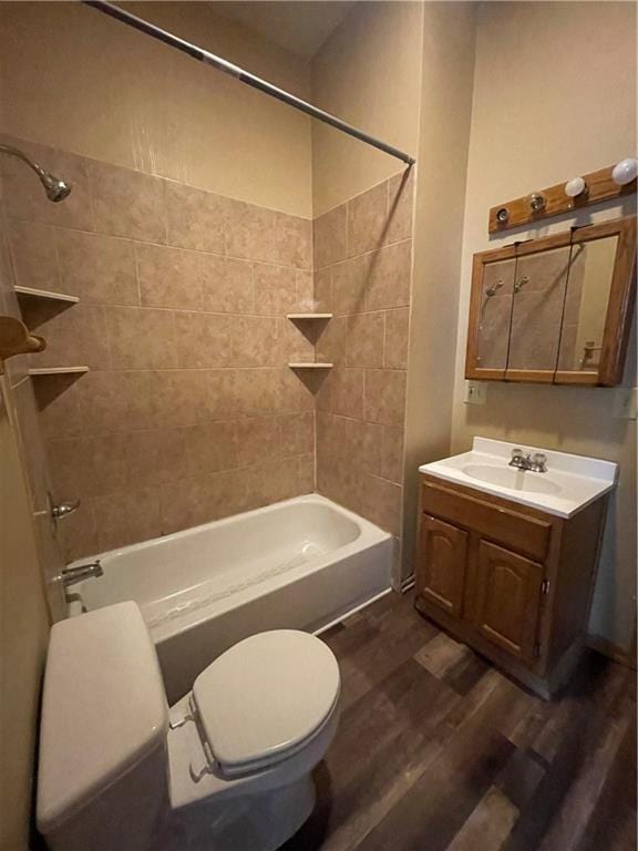 full bathroom featuring hardwood / wood-style flooring, tiled shower / bath combo, toilet, and vanity