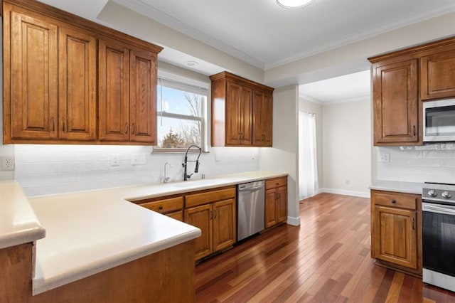 kitchen with sink, appliances with stainless steel finishes, ornamental molding, dark hardwood / wood-style flooring, and decorative backsplash