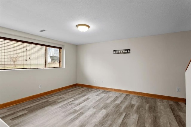 unfurnished room with wood-type flooring and a textured ceiling