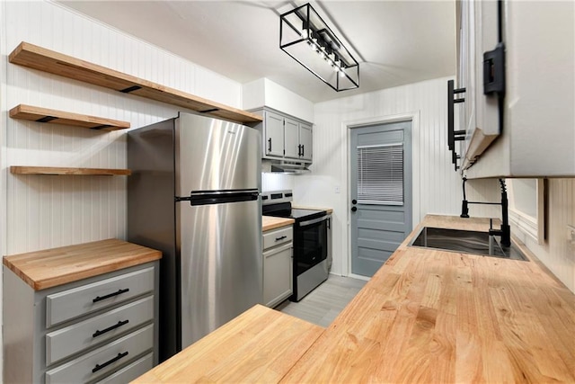 kitchen featuring gray cabinetry, sink, light hardwood / wood-style flooring, butcher block counters, and stainless steel appliances