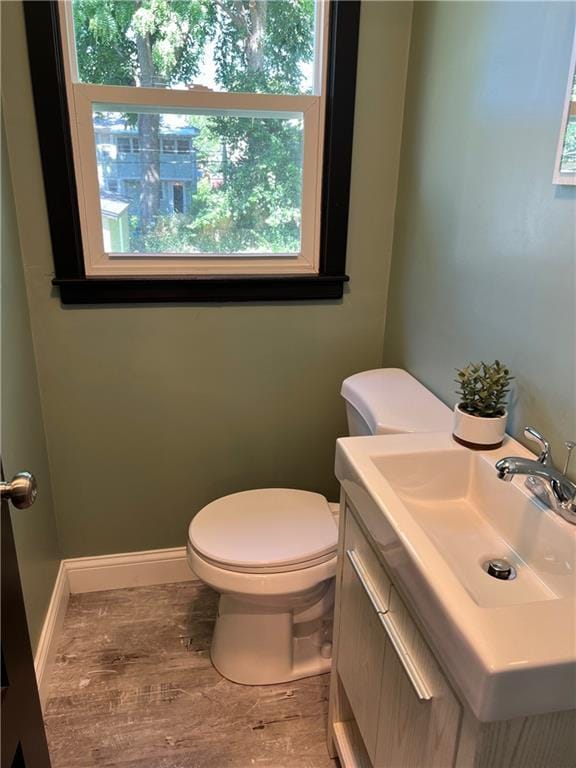 bathroom with wood-type flooring, toilet, a wealth of natural light, and sink