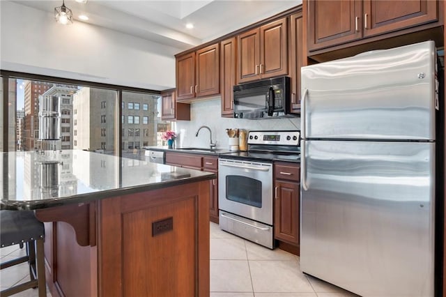 kitchen with sink, decorative backsplash, light tile patterned floors, appliances with stainless steel finishes, and a breakfast bar area