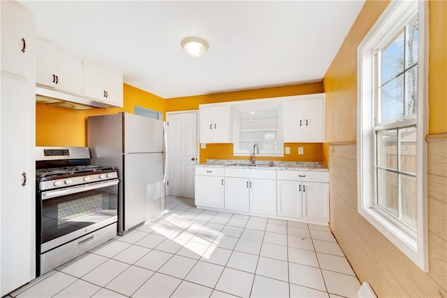 kitchen featuring sink, light tile patterned floors, stainless steel range with gas cooktop, white fridge, and white cabinets