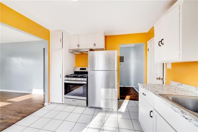 kitchen featuring gas range oven, white cabinets, stainless steel refrigerator, and light hardwood / wood-style floors