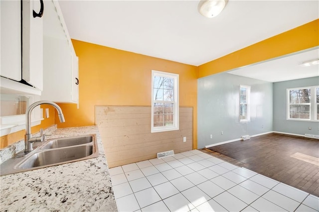 kitchen with plenty of natural light, white cabinetry, light wood-type flooring, and sink