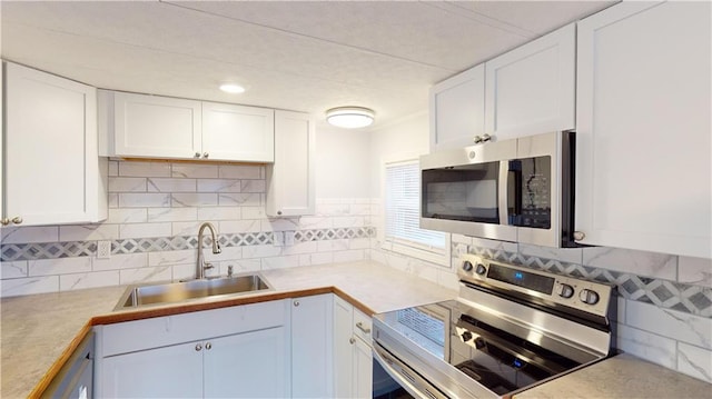 kitchen with white cabinets, backsplash, sink, and appliances with stainless steel finishes