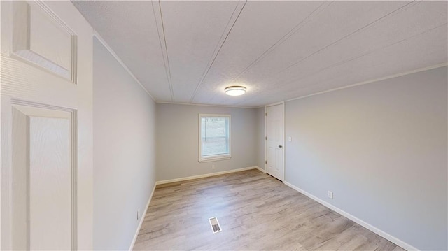 spare room featuring crown molding and light hardwood / wood-style floors