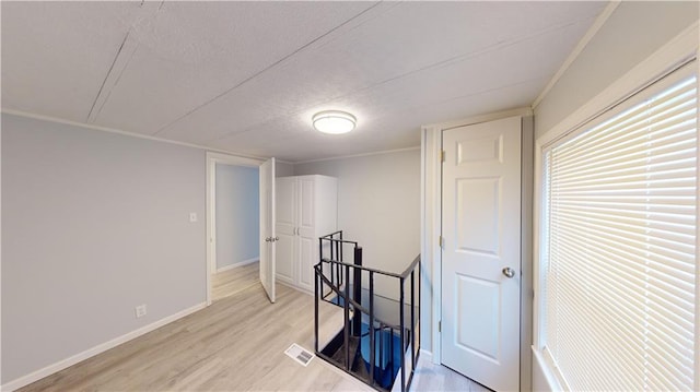 interior space with ornamental molding, a textured ceiling, and light wood-type flooring