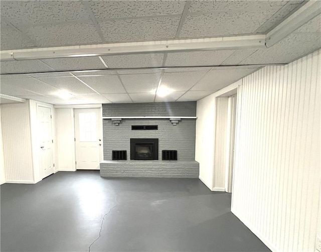 basement featuring a drop ceiling and a brick fireplace