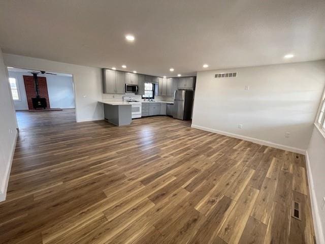 unfurnished living room with a wood stove and dark wood-type flooring