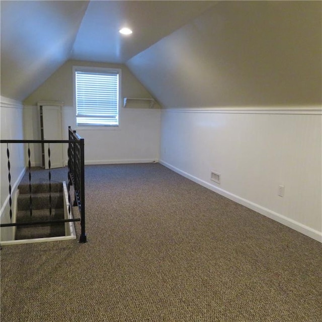 additional living space featuring dark carpet and lofted ceiling