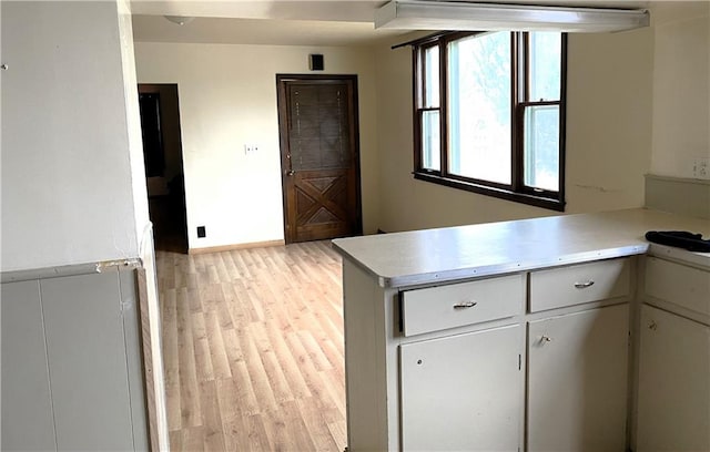 kitchen with light hardwood / wood-style floors, white cabinetry, and kitchen peninsula