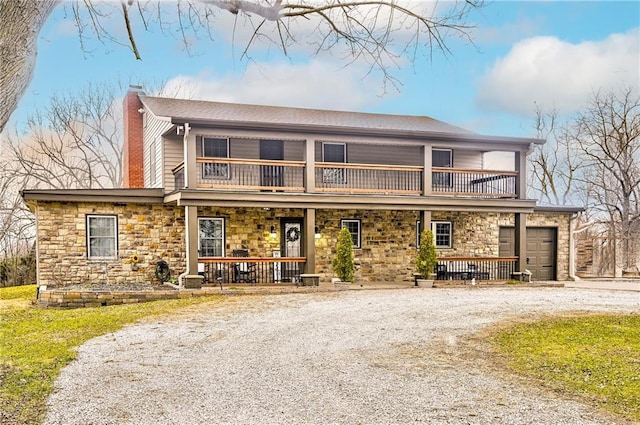 front of property with covered porch, a garage, and a balcony