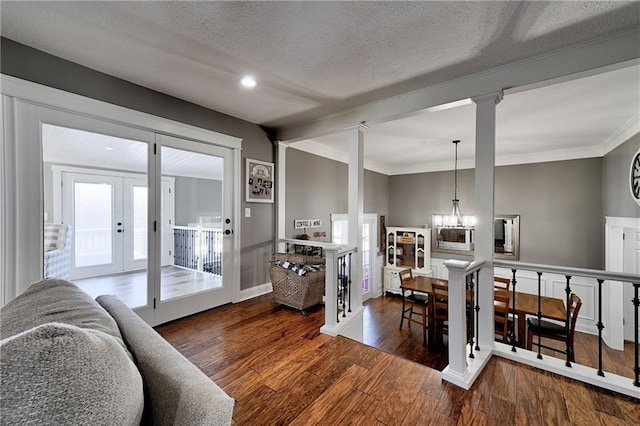 interior space featuring ornate columns, dark hardwood / wood-style flooring, ornamental molding, a textured ceiling, and french doors