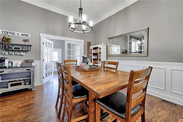 dining space featuring crown molding, dark hardwood / wood-style floors, a notable chandelier, and french doors