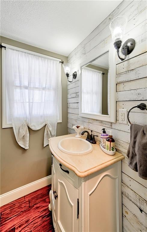 bathroom featuring vanity, hardwood / wood-style flooring, wooden walls, and a textured ceiling