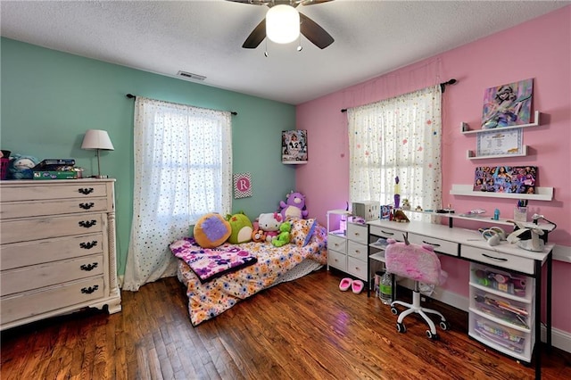 bedroom with ceiling fan, dark hardwood / wood-style floors, and a textured ceiling