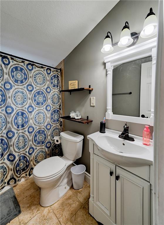 bathroom featuring walk in shower, toilet, vaulted ceiling, a textured ceiling, and vanity