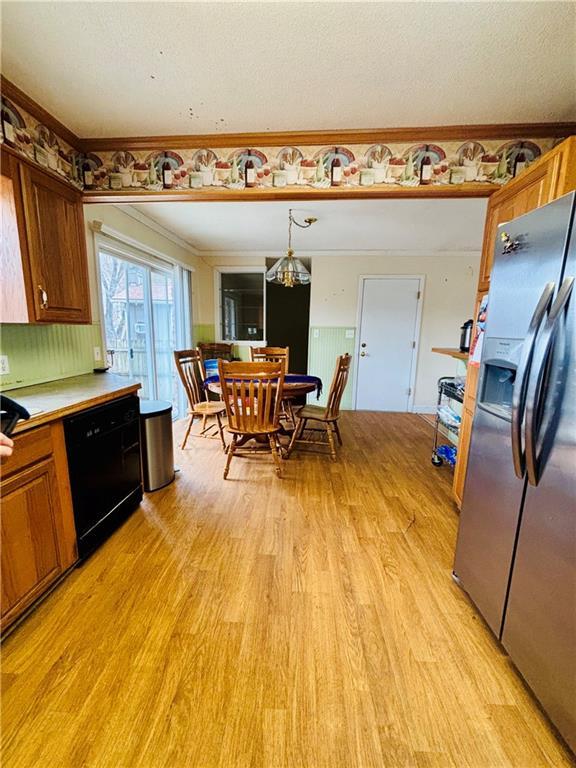 kitchen featuring stainless steel fridge with ice dispenser, dishwasher, decorative light fixtures, and light wood-type flooring