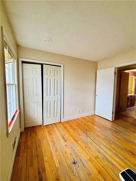 unfurnished bedroom featuring light hardwood / wood-style floors, a textured ceiling, and a closet