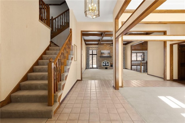 tiled entrance foyer featuring beam ceiling, a brick fireplace, and a notable chandelier