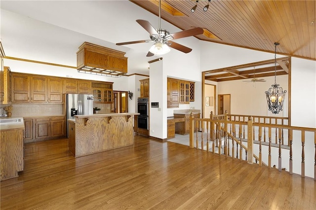 kitchen with a kitchen island, double oven, tasteful backsplash, light hardwood / wood-style floors, and stainless steel refrigerator with ice dispenser