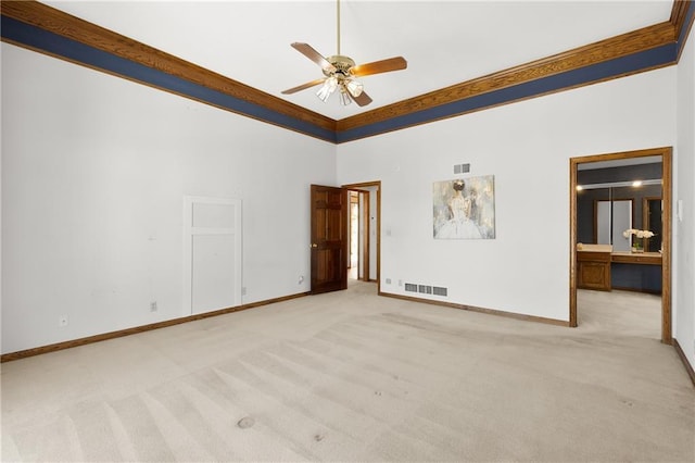 carpeted spare room with a high ceiling, ornamental molding, and ceiling fan