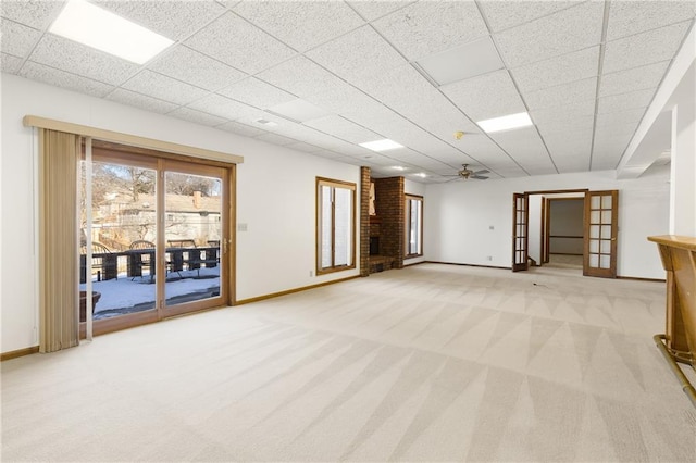 unfurnished living room featuring ceiling fan, light colored carpet, a fireplace, and a paneled ceiling